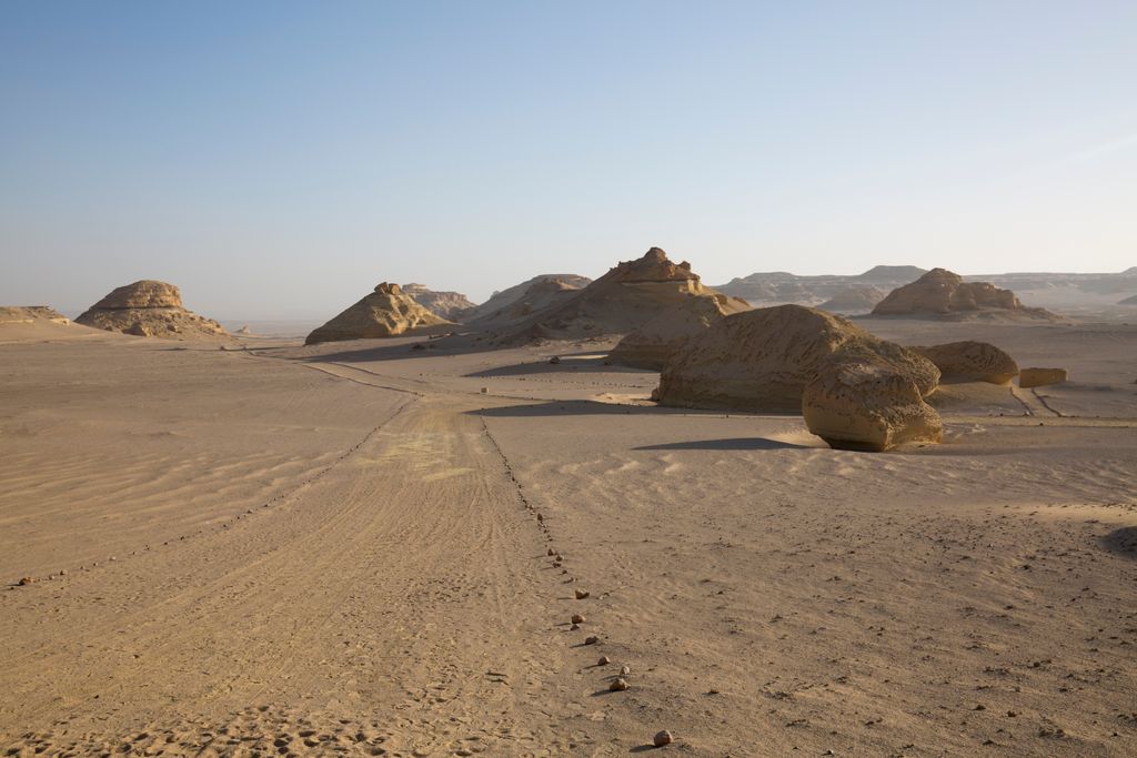 Expansive desert landscape featuring unique rock formations and a clear blue sky.